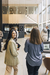 Smiling businesswoman walking with female entrepreneur in lobby at convention center