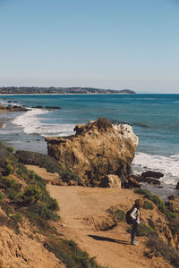 High angle view of mid adult woman standing on cliff against sea