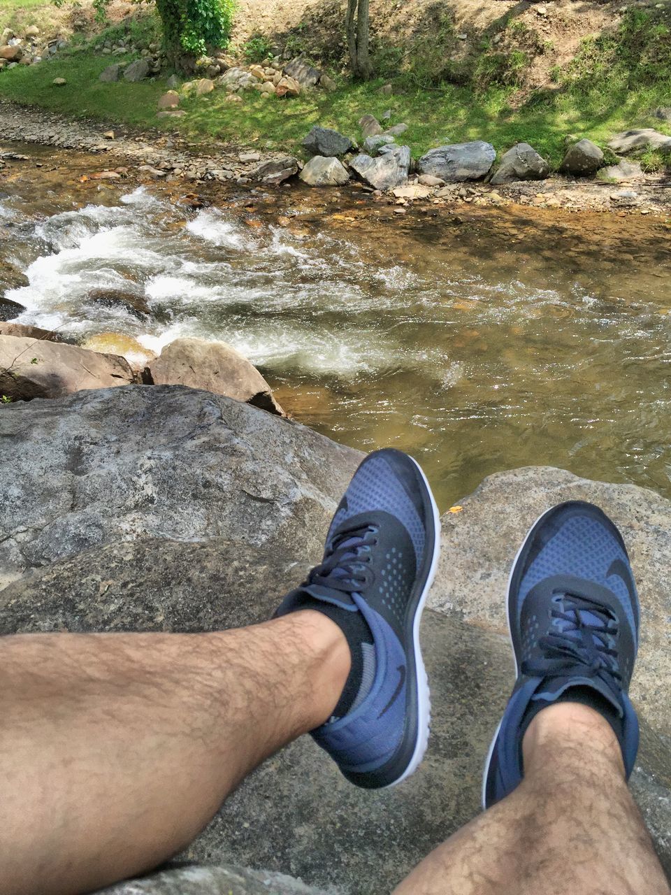 low section, person, personal perspective, shoe, water, human foot, lifestyles, leisure activity, standing, high angle view, footwear, jeans, rock - object, relaxation, outdoors, day, unrecognizable person