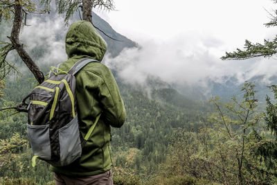 Rear view of male hiker standing against mountains