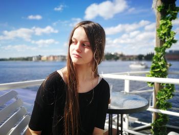 Beautiful young woman standing by sea against sky