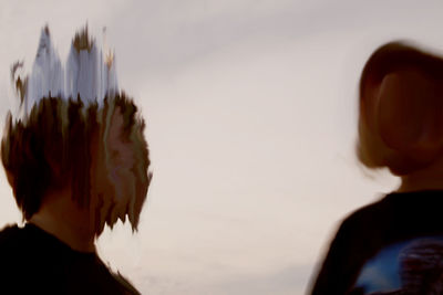 Close-up rear view of couple against sky during sunset