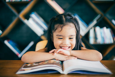 Portrait of girl with book on table