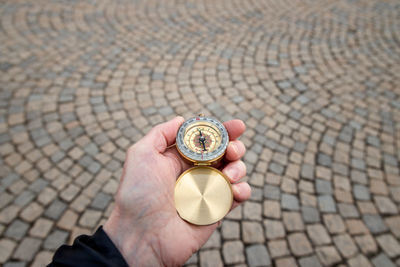 Close-up of hand holding navigational compass on footpath