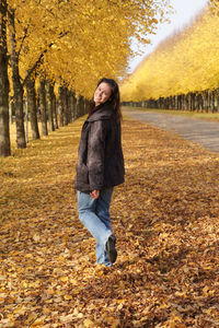 Portrait of woman walking on field covered with autumn leaves at herrenhausen gardens