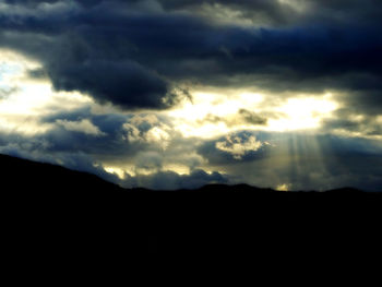 Scenic view of silhouette mountains against dramatic sky