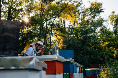 Beekeepers standing by containers during sunset