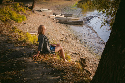 Side view of woman sitting on shore