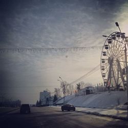 Cars on road against cloudy sky