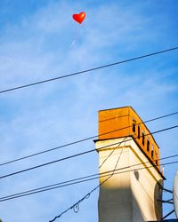 Low angle view of balloons against building against sky