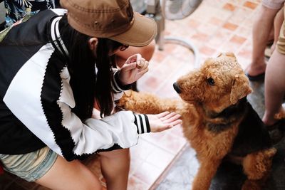 Side view of woman playing with dog at sidewalk