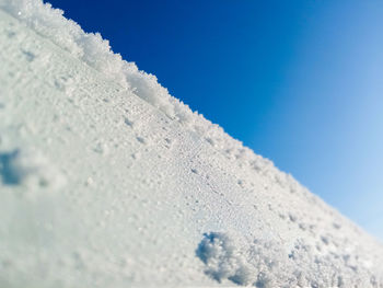 Close-up of snow covered against blue sky