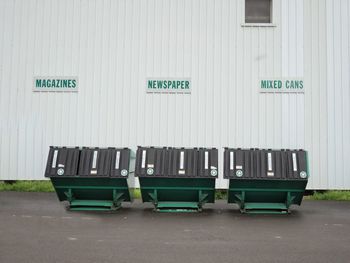 Row of recycling bins against exterior wall