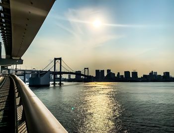 Bridge over river in city against sky during sunset