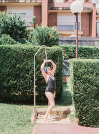 Full length of young woman taking shower in yard