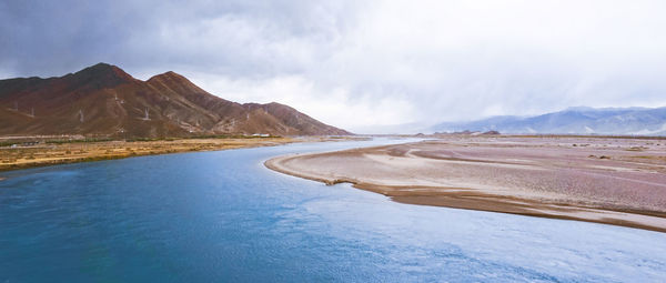 Scenic view of lake by mountains against sky