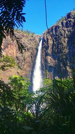 Low angle view of waterfall against clear sky