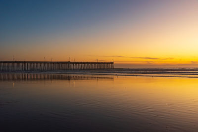 Pier over sea against sky during sunset