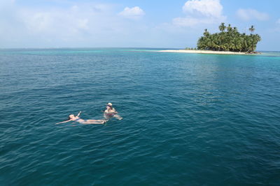 Couple swimming in sea against sky