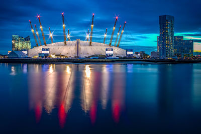 Illuminated pier by sea against sky in city