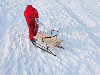High angle view of person pulling sled on snow covered field