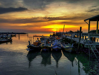 View of fishing boats in harbor at sunset