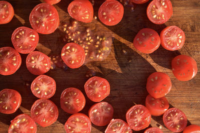 Above view of red grape tomatoes cut into halves on wood cutting board