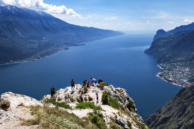 High angle view of people on rocks by mountain against sky