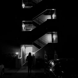 Rear view of silhouette man walking in illuminated building at night