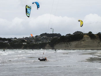 People paragliding over sea against sky