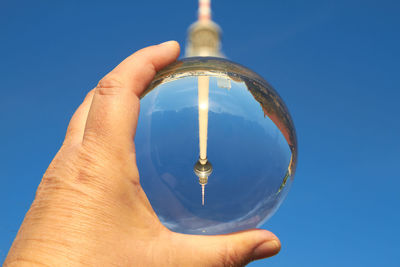 Cropped hand holding crystal ball against fernsehturm