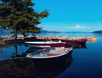 Boat moored in sea against blue sky