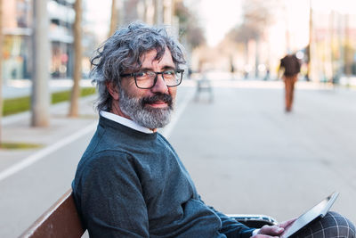 Portrait of young man sitting on street in city