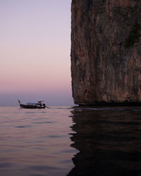 Boat sailing in sea against clear sky during sunset