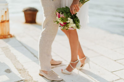 Low section of bride and groom standing on footpath