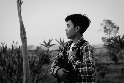 Young man looking away while standing on field