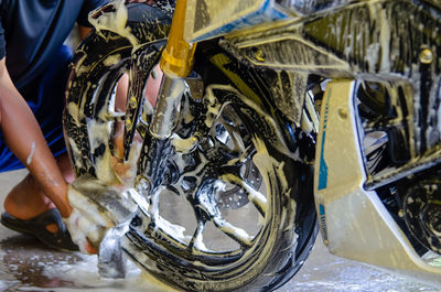 Low section of man cleaning motorcycle in garage