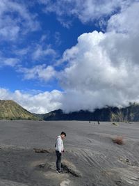 Rear view of man standing on mountain against sky