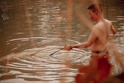 Young man splashing water in lake