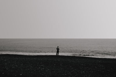 Silhouette man standing on beach against clear sky