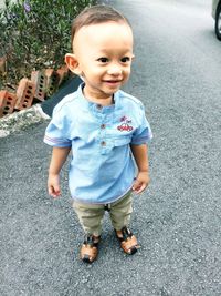 Cute baby boy standing on road