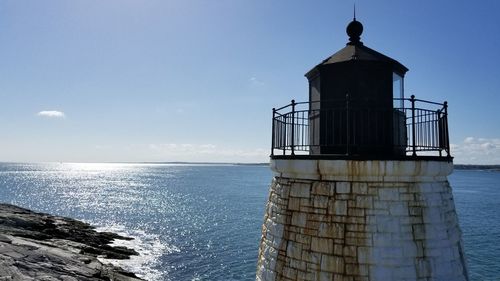 Lighthouse by sea against sky