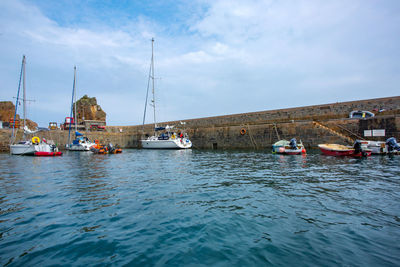 Boats moored at harbor against sky