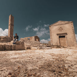 Full length of boy sitting against old building