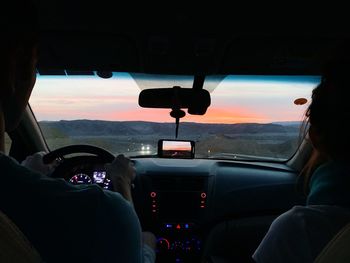 People seen through car windshield at sunset