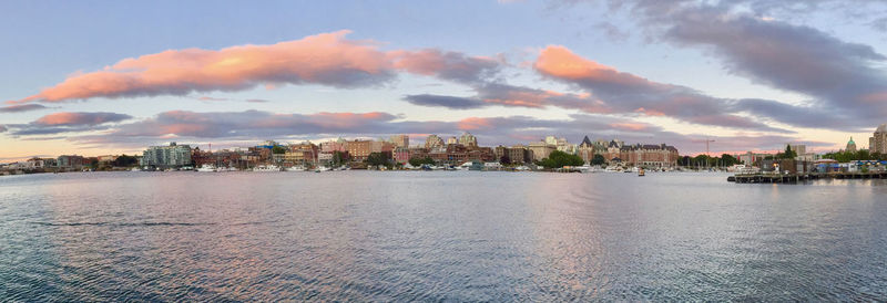 City by sea against sky at sunset