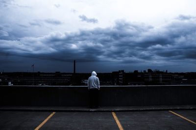 Rear view of man standing on road against sky