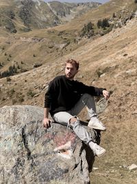 Young man standing on rock against mountains