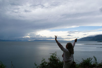 Rear view of woman looking at sea against sky