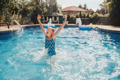 Girl swimming splashing in pool on home backyard. summer outdoor water activity for kids.